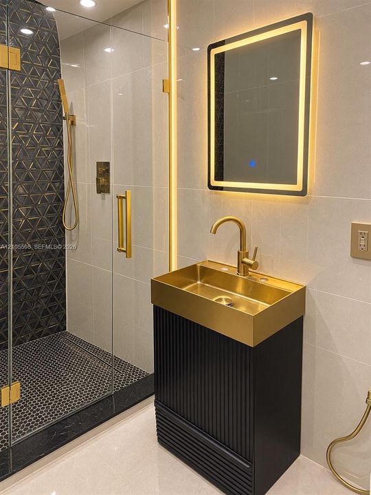 Floating vanity with a gold-finish basin and fluted black cabinetry
