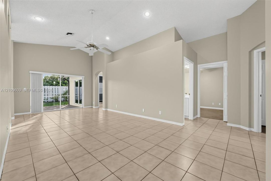 Interior space featuring vaulted ceilings, tile flooring, recessed lighting, a ceiling fan, and sliding glass doors