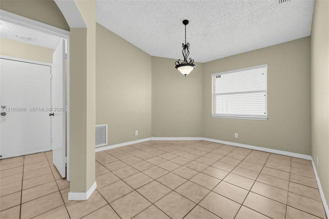 Neutral wall paint, tiled flooring, iron-finish pendant lighting, and horizontal window blinds