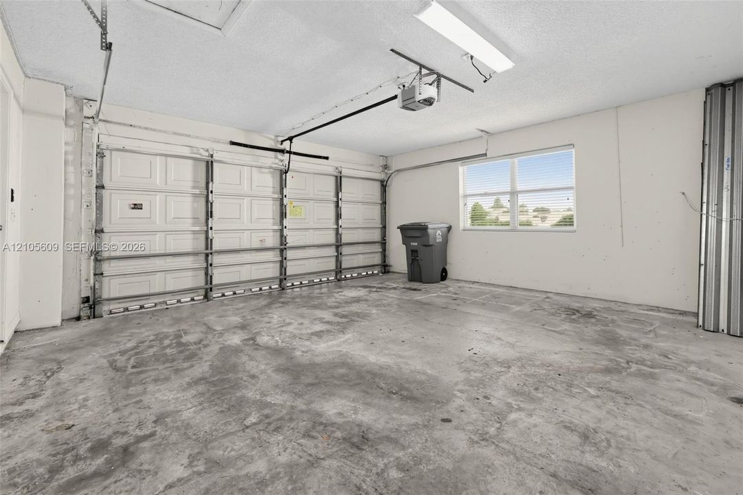 Enclosed multi-car garage featuring a sectional metal door, concrete flooring, overhead light fixture, and a window with exterior exposure