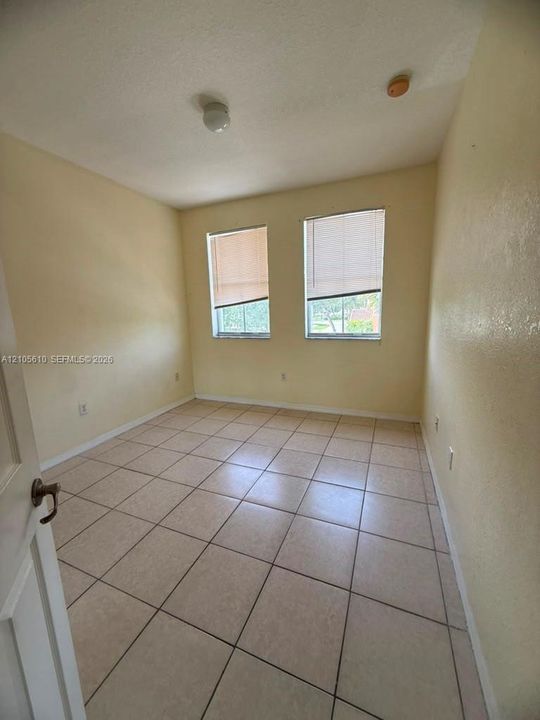 Room with neutral wall finish, large-format tile flooring, and two dual-pane windows