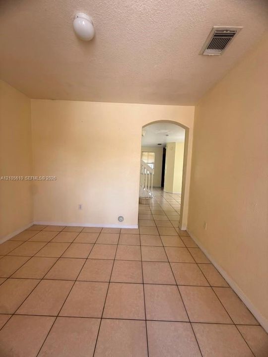 Interior space featuring neutral-toned tile flooring and a distinctive arched doorway