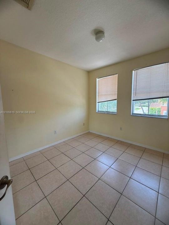 Neutral wall tones, ceramic tile flooring, and two windows with horizontal blinds