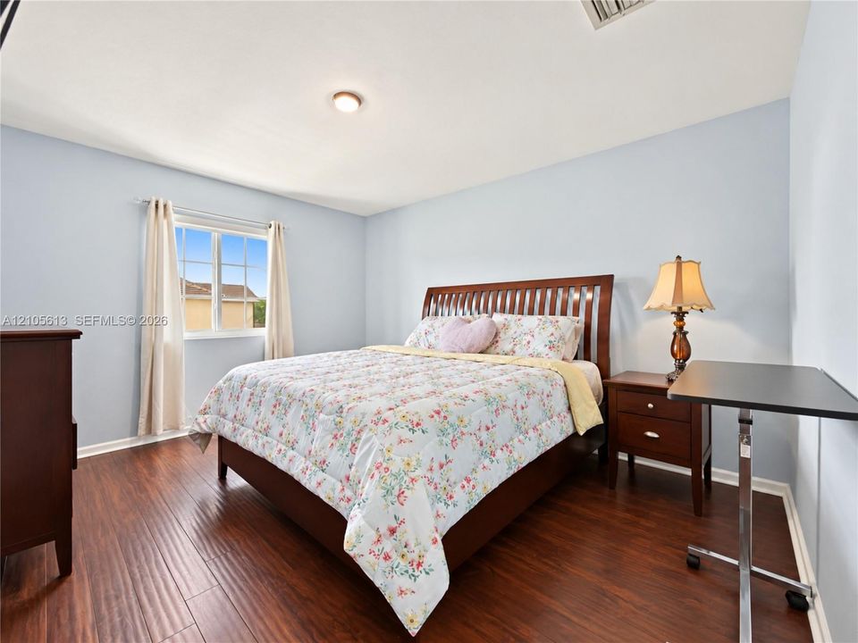 Bedroom featuring wood-finish flooring, a multi-pane window, and a central ceiling light fixture