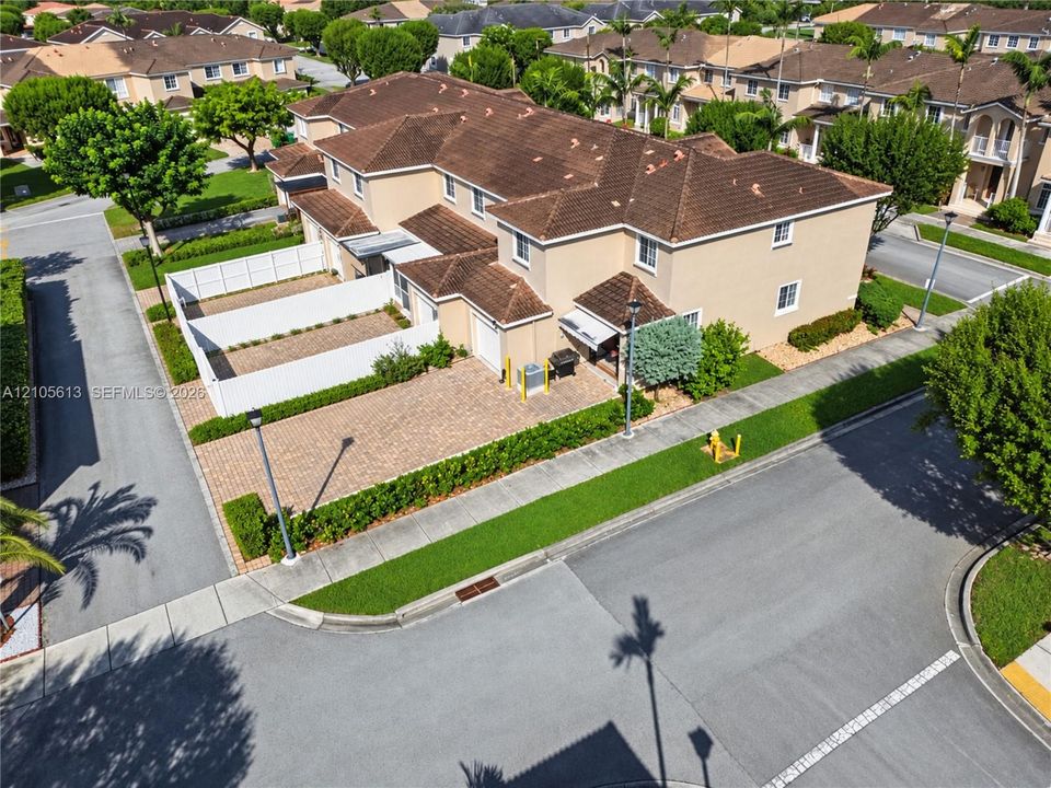 Multi-level residence featuring a textured tile roof, stucco exterior, paver driveway, and a private enclosed courtyard area