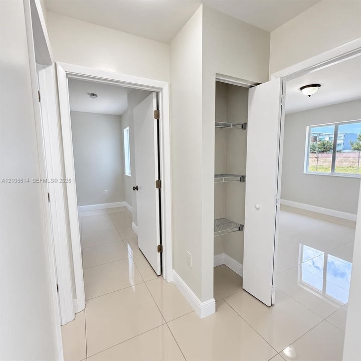 Polished large-format tile flooring, built-in wire shelving storage, and neutral wall tones