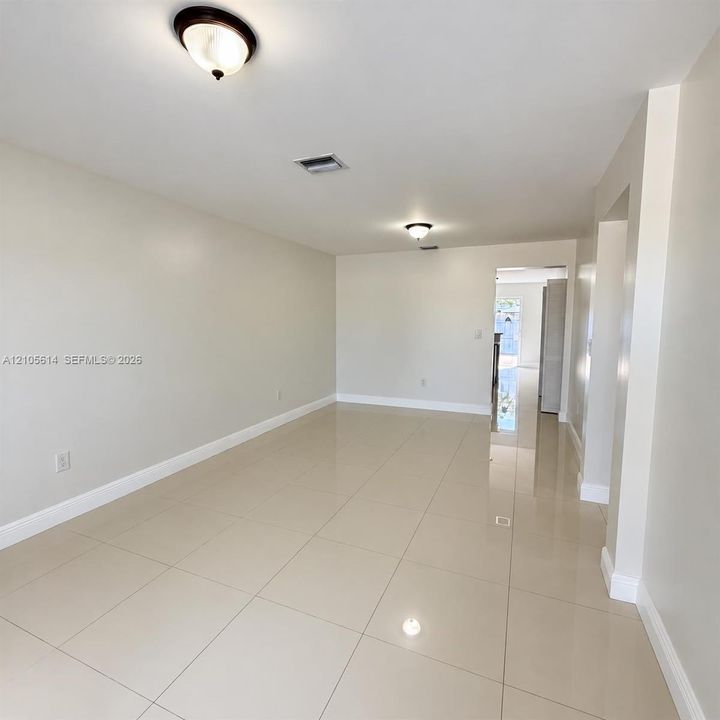 Neutral-toned interior featuring large-format ceramic tile flooring, smooth walls, and dual semi-flush mount light fixtures