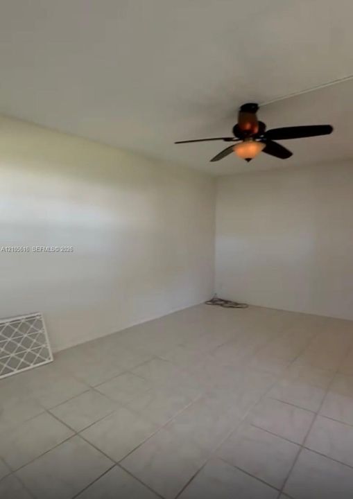 Neutral interior space featuring light-toned tile flooring and a ceiling-mounted fan with integrated light fixture