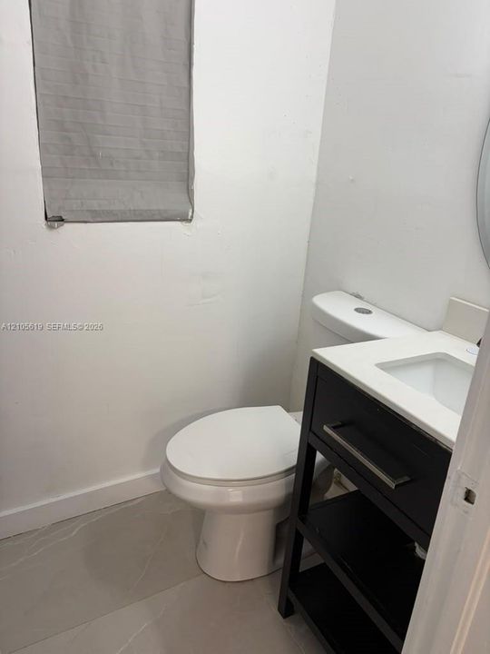 Dark-finish vanity featuring an integrated white sink and countertop, paired with large-format light-toned tile flooring