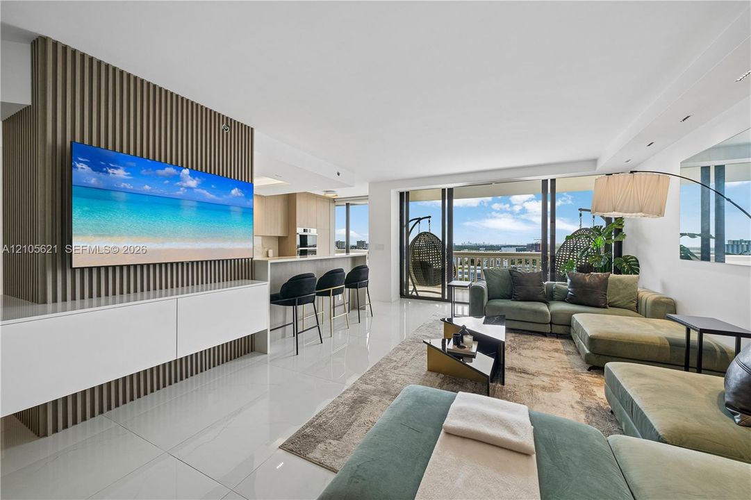 Living area featuring a vertical wood-slat accent wall, polished tile flooring, built-in white cabinetry, recessed ceiling lighting, and floor-to-ceiling glass sliding doors