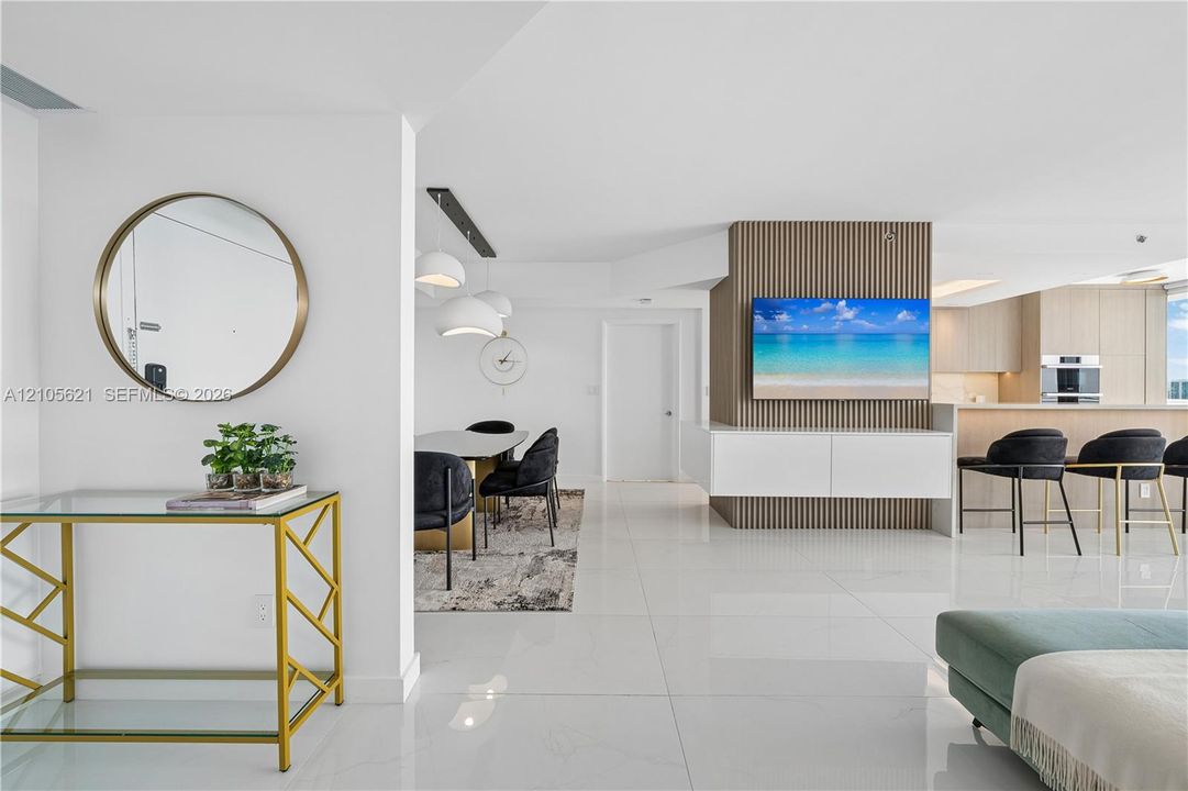 Open-concept interior featuring large-format tile flooring, vertical wood-slat accent wall, and integrated cabinetry