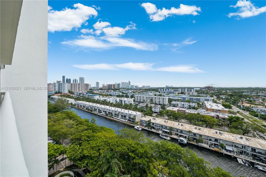 Elevated balcony featuring a panoramic cityscape, canal waterway, and mature tree canopy