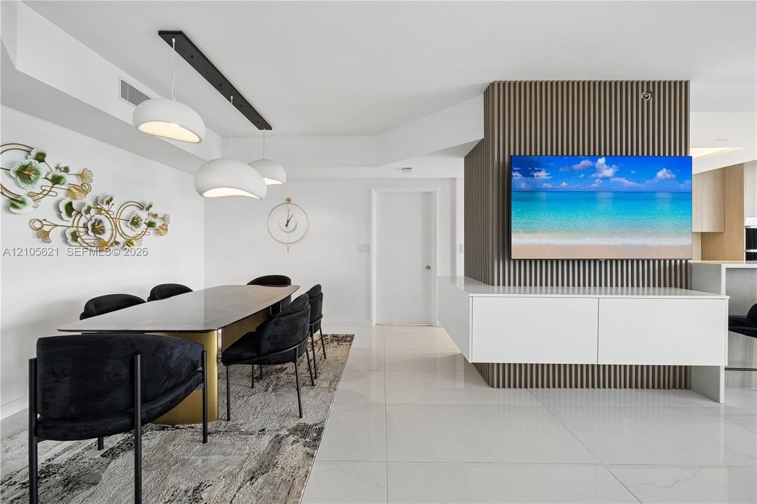 Modern interior featuring a vertical wood-slat accent wall, high-gloss tile flooring, three-pendant track lighting, and a white, wall-mounted floating storage console