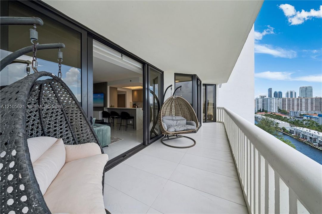 Expansive covered balcony featuring large-format tile flooring, a white metal railing, and floor-to-ceiling multi-panel sliding glass doors