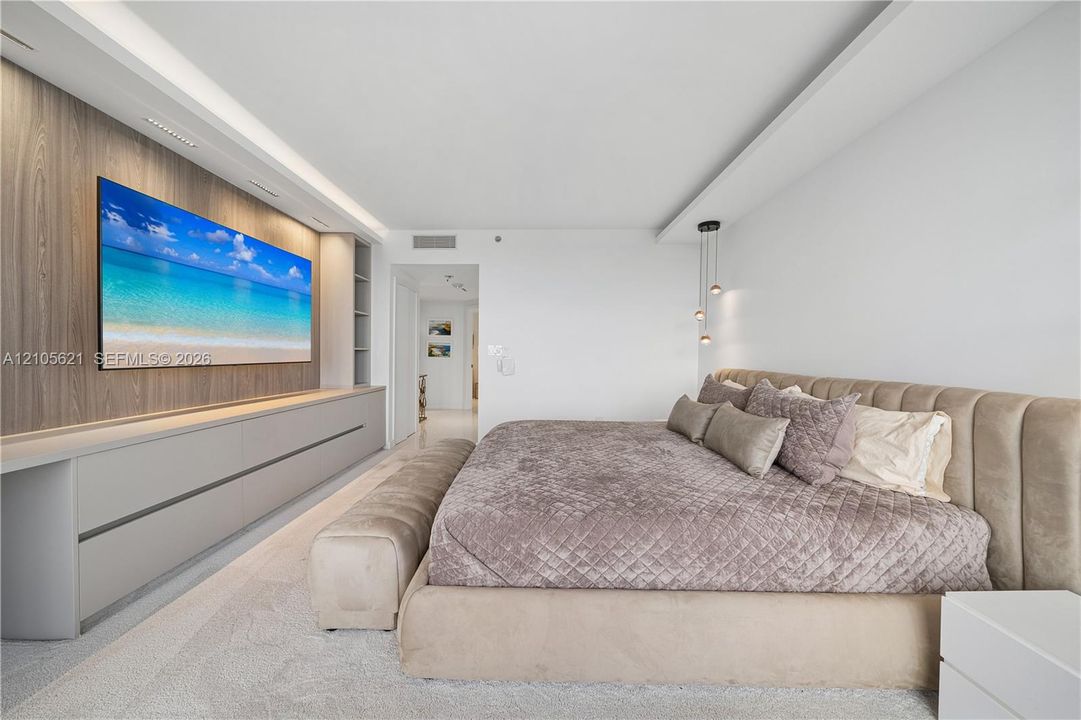 Custom wall-to-wall cabinetry with wood-finish paneling, minimalist ceiling crown molding, neutral wall-to-wall carpeting, and tiered pendant lighting