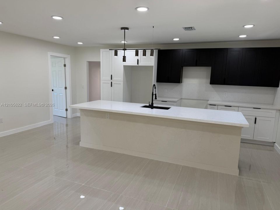 Kitchen featuring a central island with a solid surface countertop, high-contrast two-tone cabinetry, recessed ceiling lighting, and tile flooring