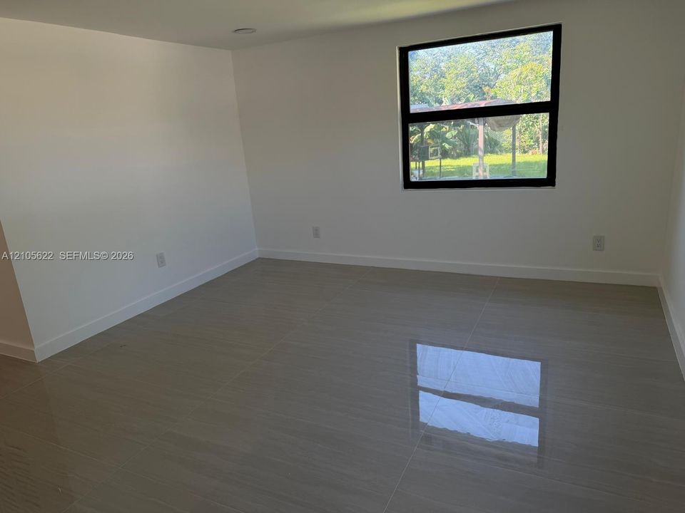 Large format tile flooring, neutral wall finishes, and a dark-framed picture window