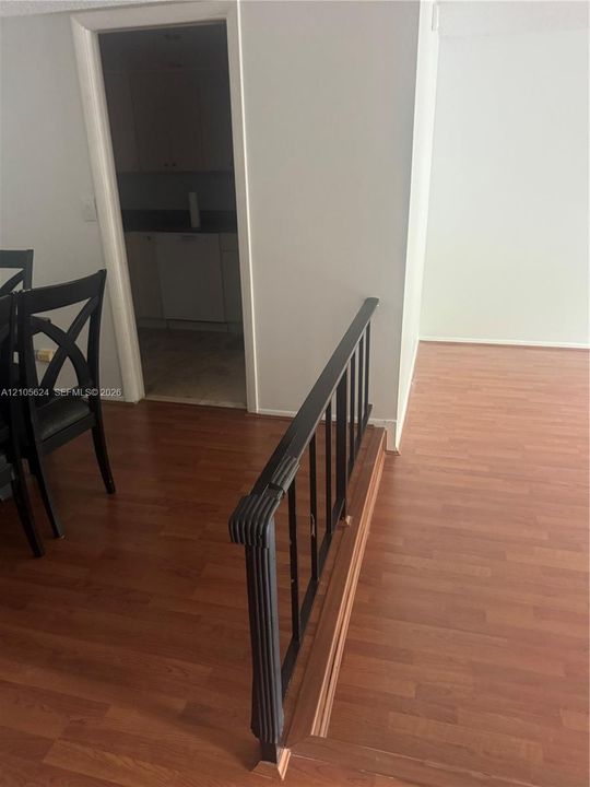 Wood-finish flooring throughout with a metal railing featuring vertical balusters