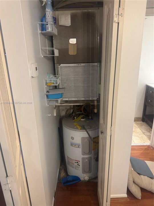Utility closet containing a vertical HVAC unit and an electric water heater