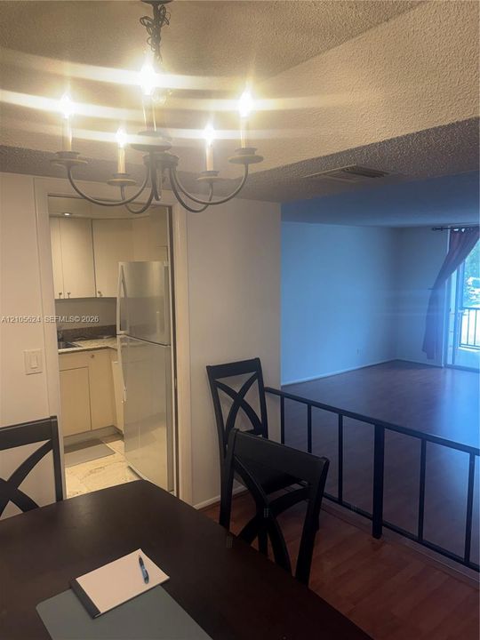 Dining area featuring a classic candelabra-style chandelier, wood-finish flooring, and a metal partition railing
