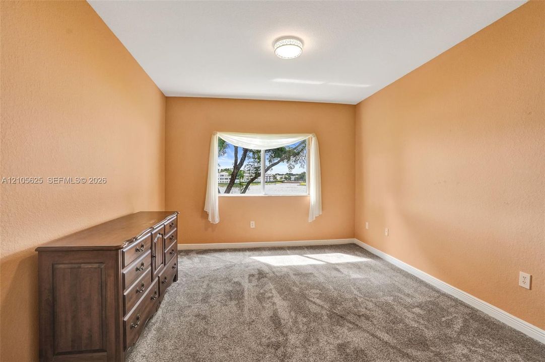 Interior space featuring neutral-toned walls, wall-to-wall carpeting, and a central ceiling-mounted light fixture, finished with a single-pane horizontal window