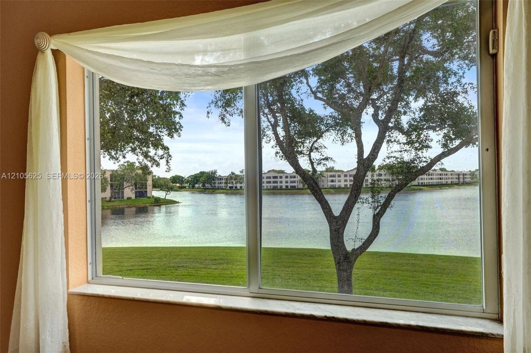 Large window with a stone-finish sill, showcasing water and green space