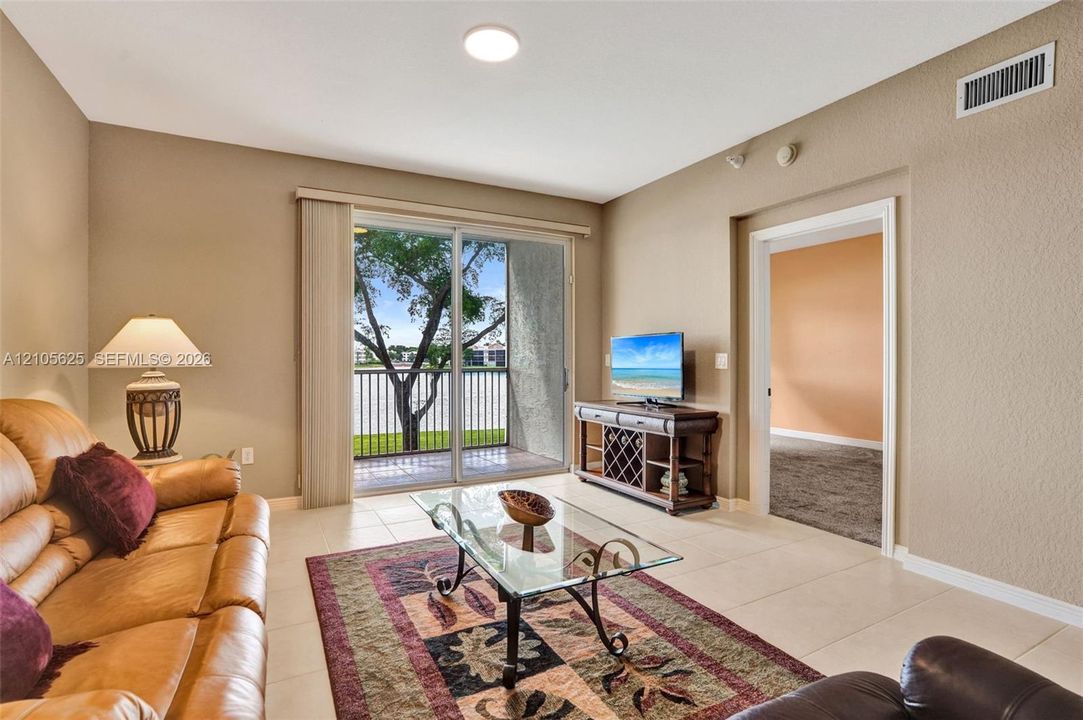 Living area featuring neutral wall paint, tile flooring, and sliding glass doors opening to a private balcony