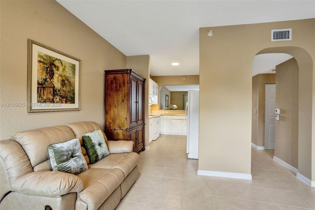 Neutral interior featuring tile flooring, an arched entryway, and white cabinetry