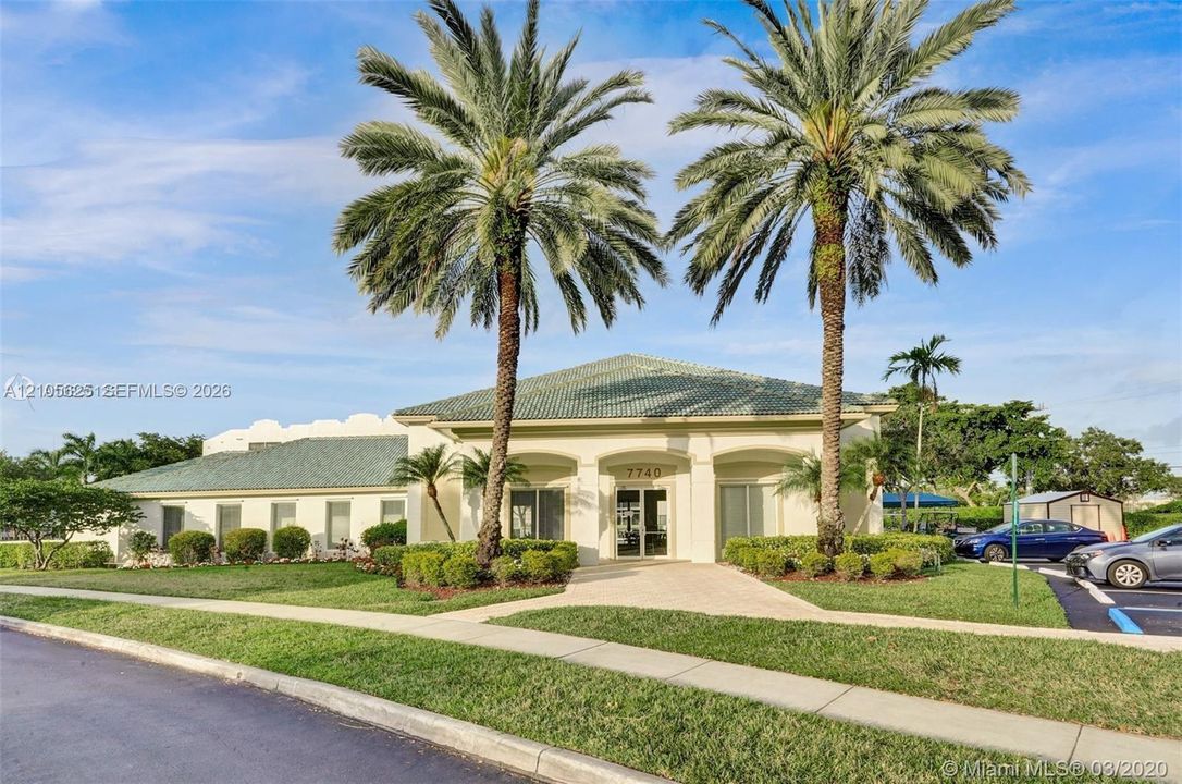 Stucco exterior featuring a multi-gabled roof, arched entryway, and mature palm landscaping
