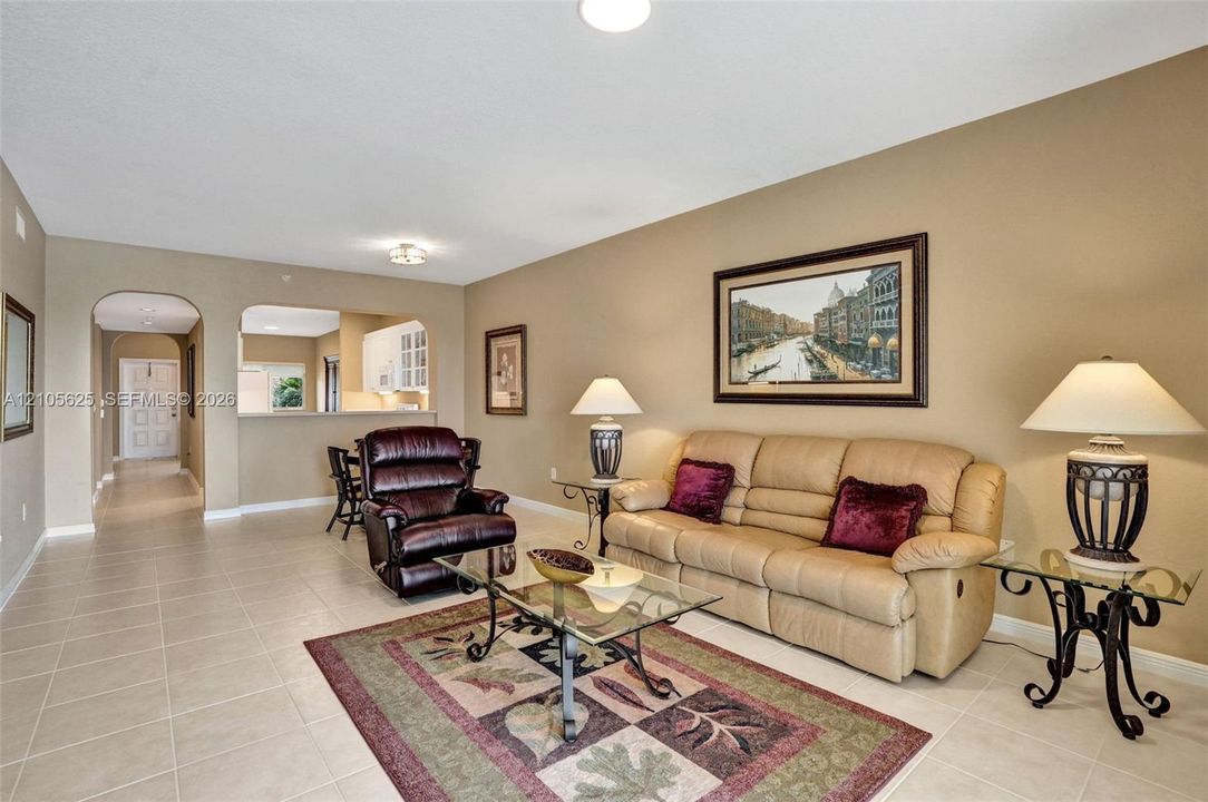 Neutral ceramic tile flooring, arched wall openings, and recessed ceiling lighting