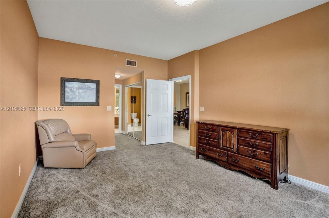 Room featuring neutral wall tones, plush carpeting, a multi-panel interior door, and a built-in closet with mirrored sliding doors