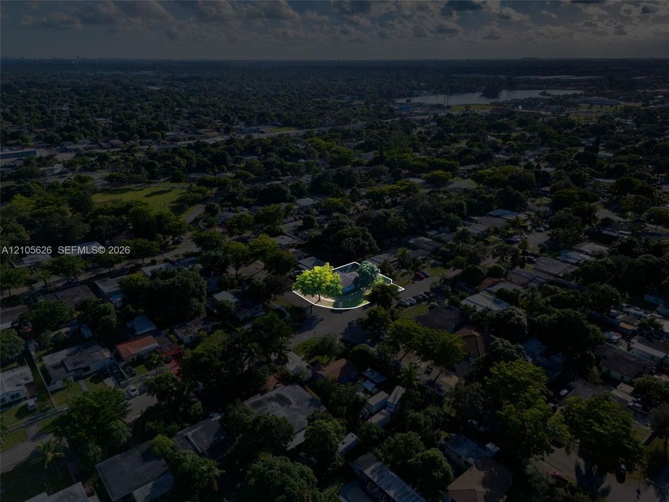 Aerial perspective of a corner lot property featuring mature shade trees and perimeter fencing