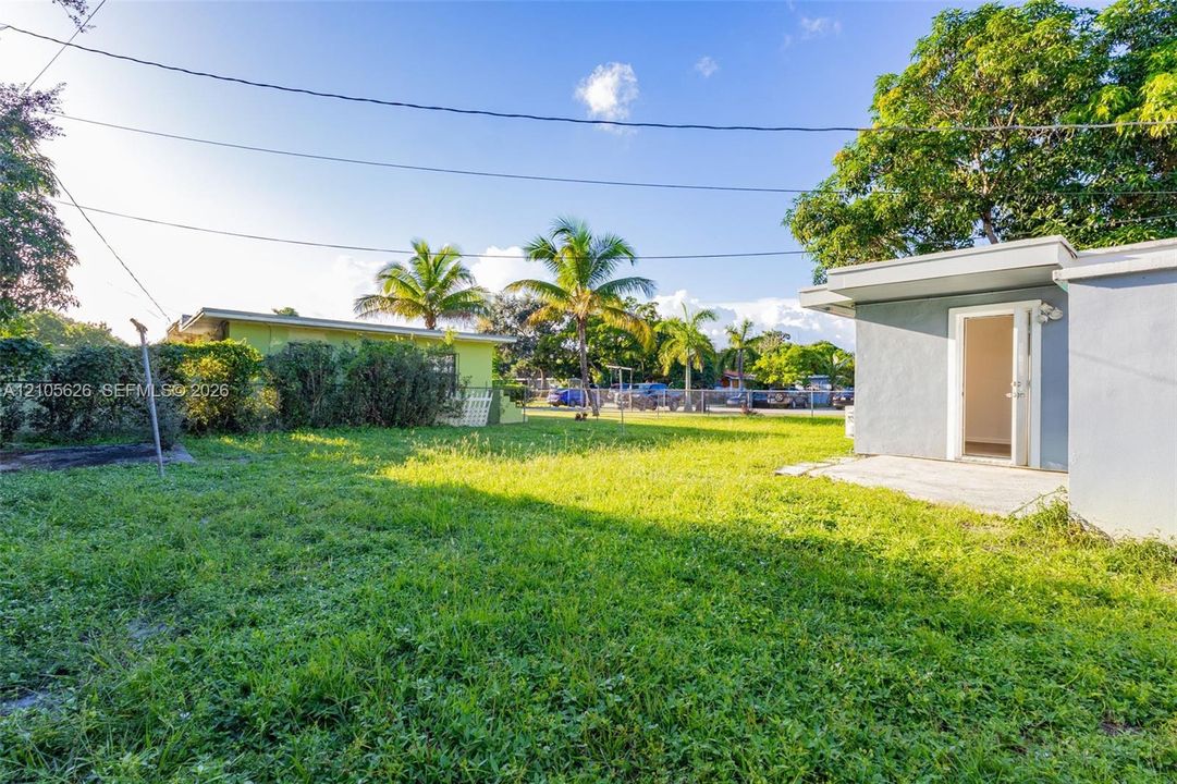 Expansive grass lawn featuring mature palm trees and concrete exterior patio