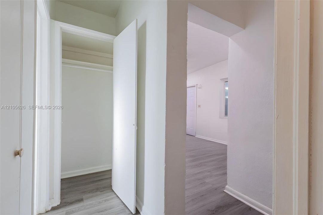 Wood-finish flooring throughout, interior closet with overhead shelving, and neutral wall tones
