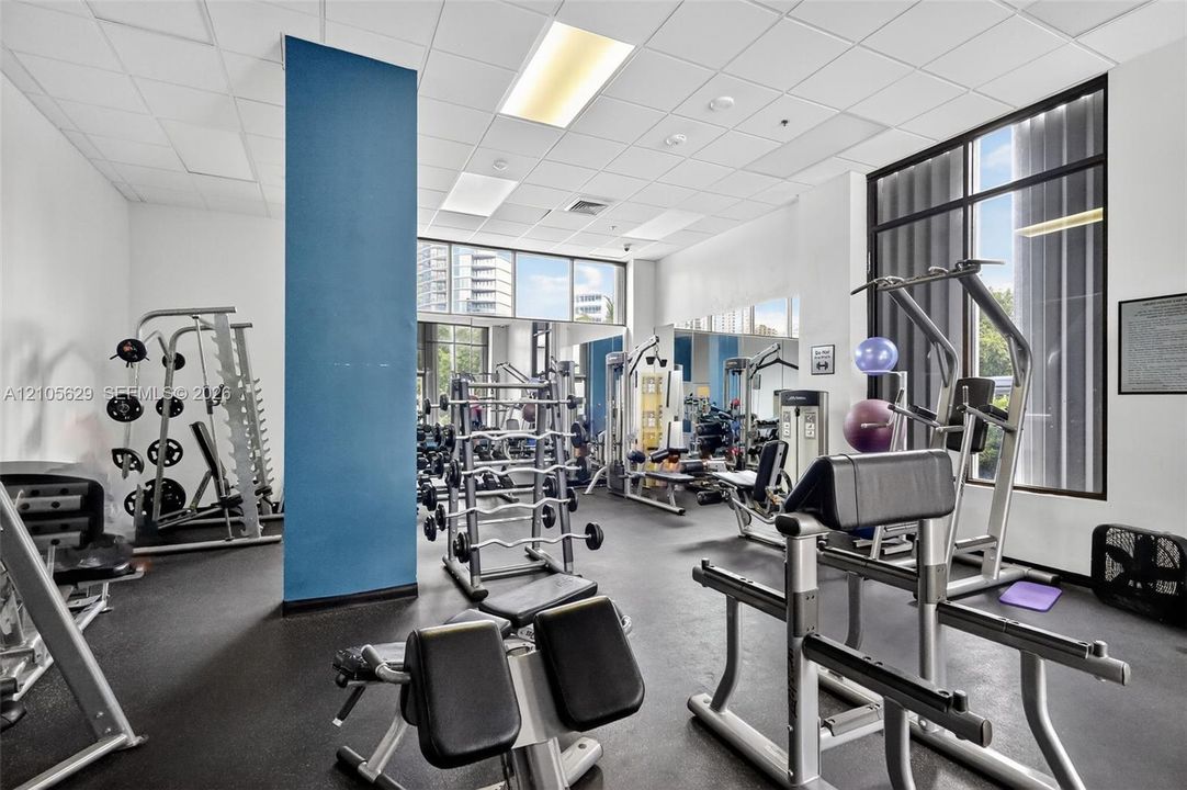 Fitness center featuring black rubberized flooring, floor-to-ceiling windows, and recessed lighting panels