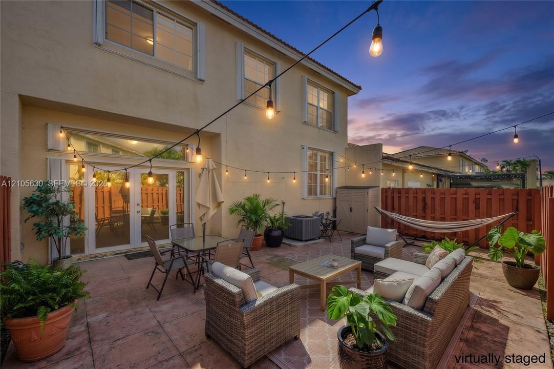 Rear exterior featuring a paved patio, perimeter wood fencing, and dual glass-paned doors
