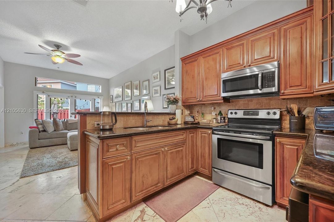 Kitchen featuring raised-panel wood cabinetry, dark stone countertops, tile backsplash, stainless steel appliances, and tile flooring