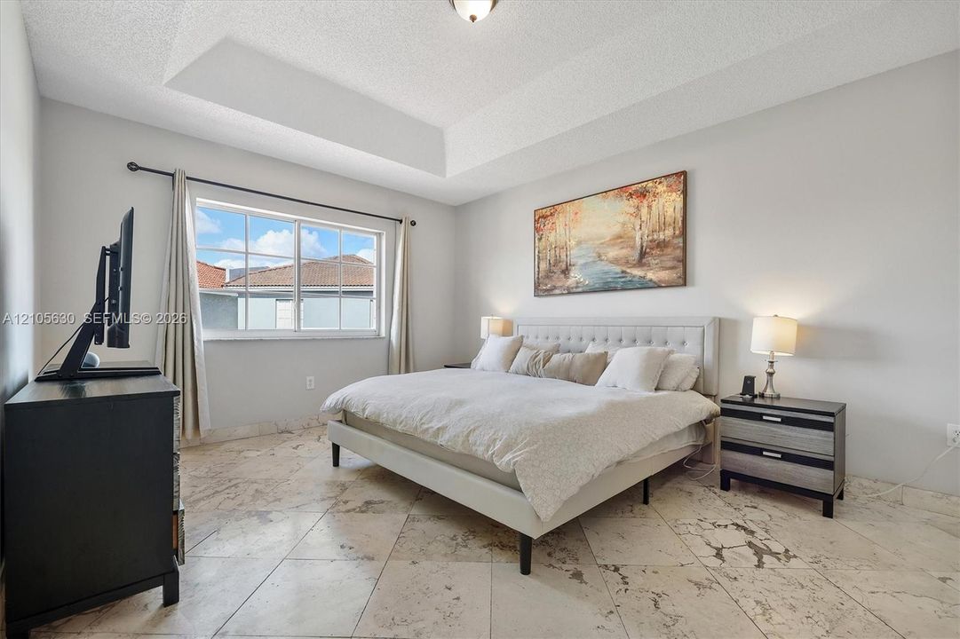Tray ceiling, neutral wall color, and light-toned tile flooring