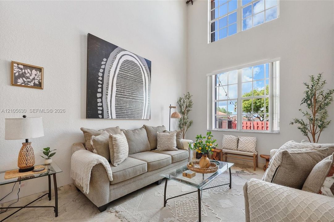 Two-story volume ceiling featuring multi-level grid windows and light-toned tile flooring
