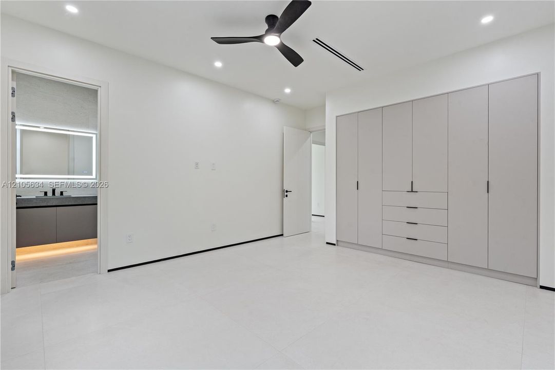 Built-in floor-to-ceiling cabinetry, recessed lighting, matte black ceiling fan, and large-format tile flooring