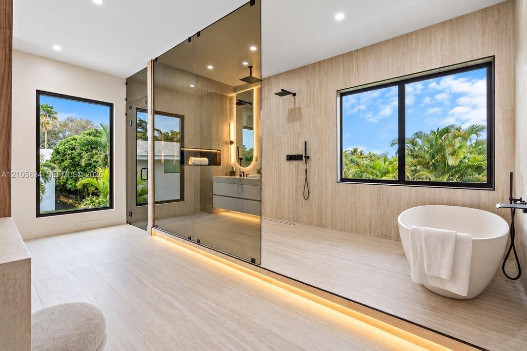 Bathroom featuring a freestanding oval soaking tub, expansive glass-enclosed shower, wood-finish wall and floor tiling, matte black fixtures, and recessed LED accent lighting