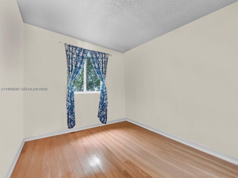 Neutral-toned interior space featuring wood-finish flooring and a single-pane window