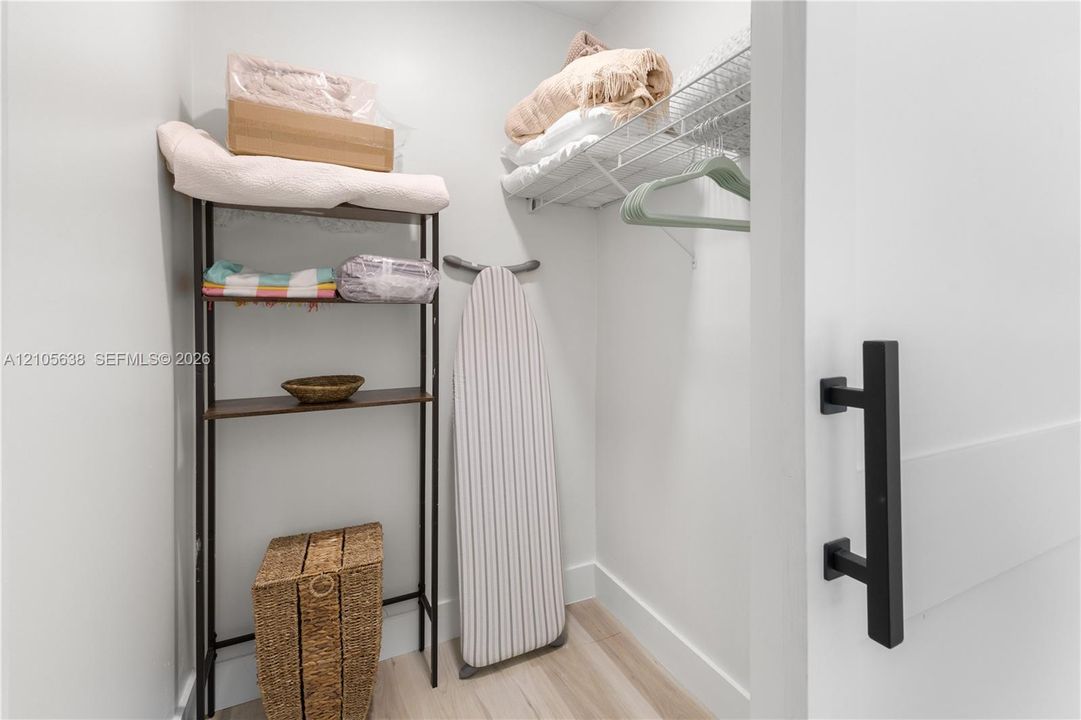 Storage closet featuring a white sliding door with matte black handle hardware and wire shelving