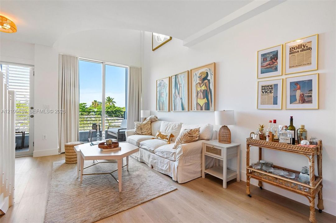 Vaulted ceilings, floor-to-ceiling glass sliding doors, wood-finish flooring, and balcony access