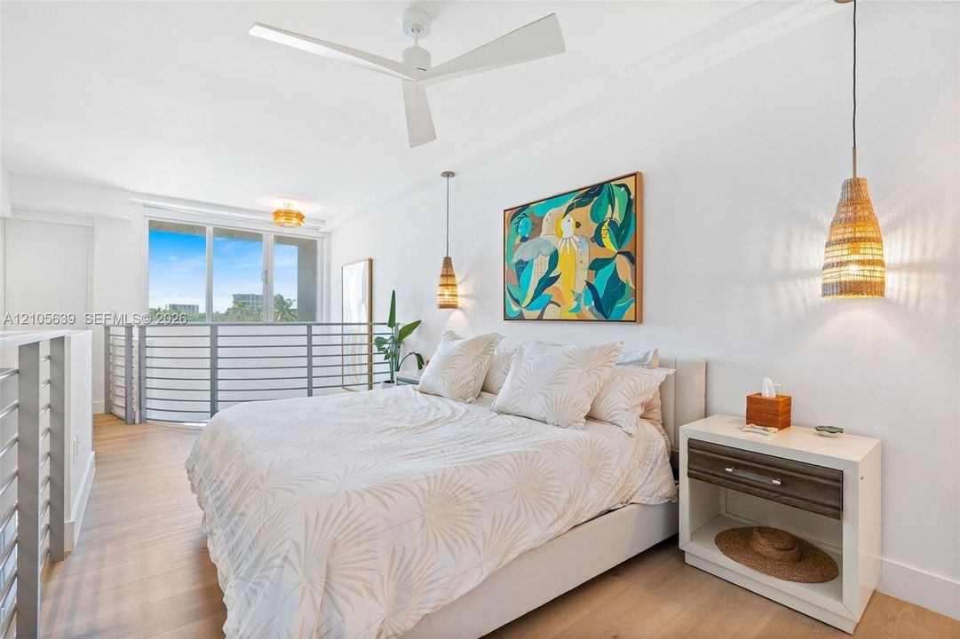 Wood-finish flooring, white three-blade ceiling fan, metal stair railing, and dual woven-shade pendant lights