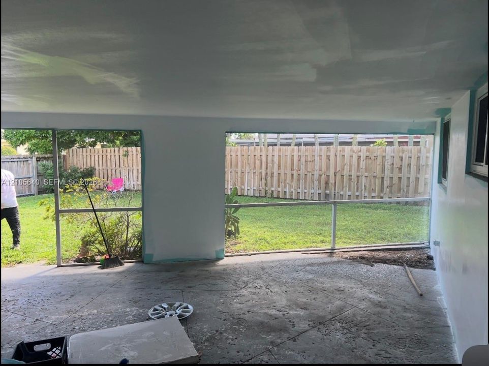 Enclosed porch featuring screen wall panels, concrete flooring, and a fenced backyard