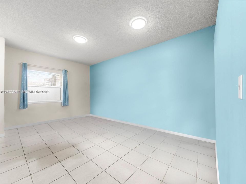 Room featuring neutral-toned ceramic tile flooring, dual flush-mount ceiling light fixtures, and a single-hung window