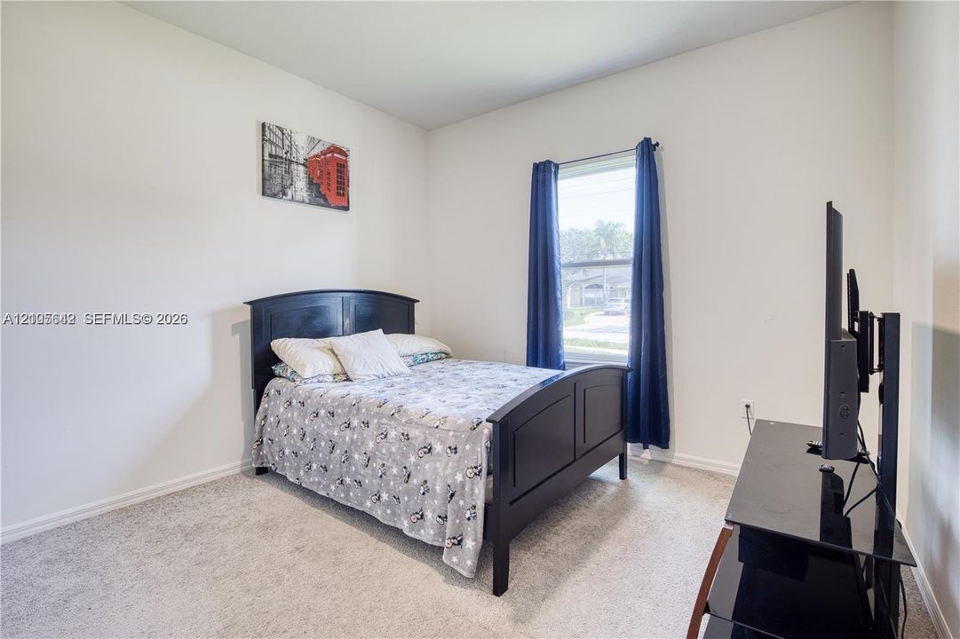 Neutral wall tones, wall-to-wall carpeting, and a large window with natural light