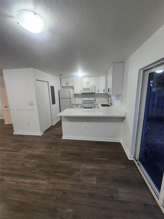 Kitchen featuring white cabinetry, solid-surface countertops, wood-finish flooring, and a sliding glass door