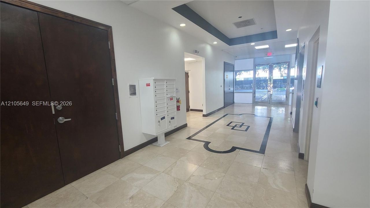 Common lobby featuring tile flooring with decorative inlay, recessed ceiling lighting, tray ceiling detail, and integrated mail collection station